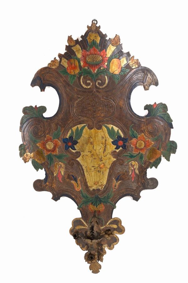 Applique a forma di scudo in legno inciso e laccato con braccio in ferro battut...