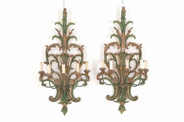 Coppia di applique cinque luci in legno intagliato e laccato con bracci in ferr...