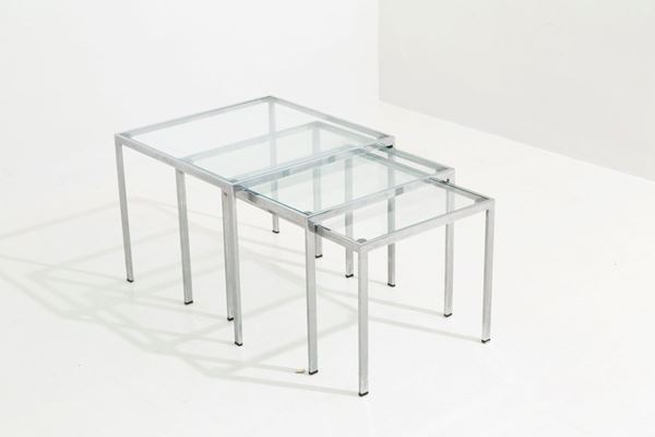 Trittico di tavolini quadrati in metallo cromato con piano in vetro. Manifattur...