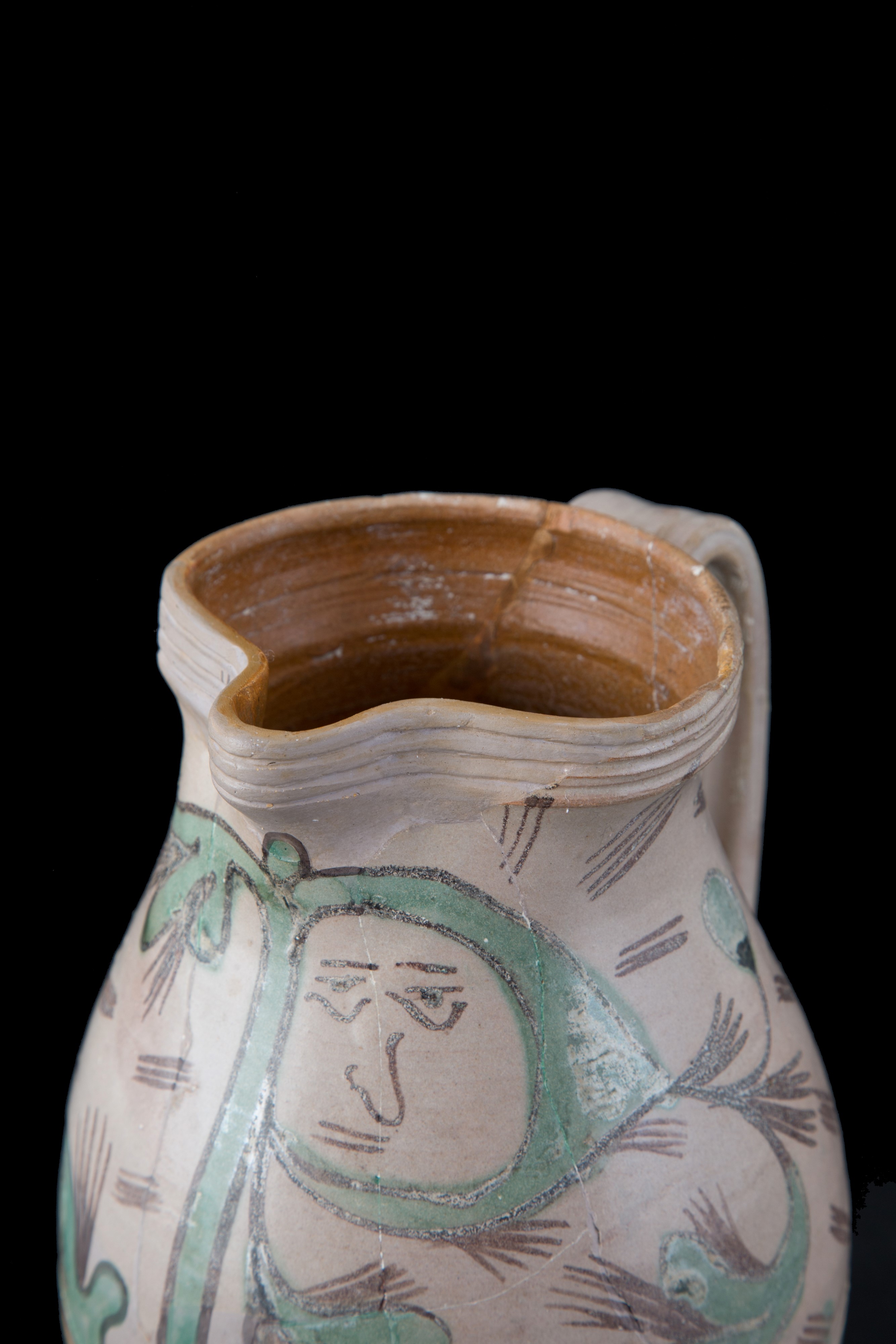 Brocca in maiolica con volto tra i tralci