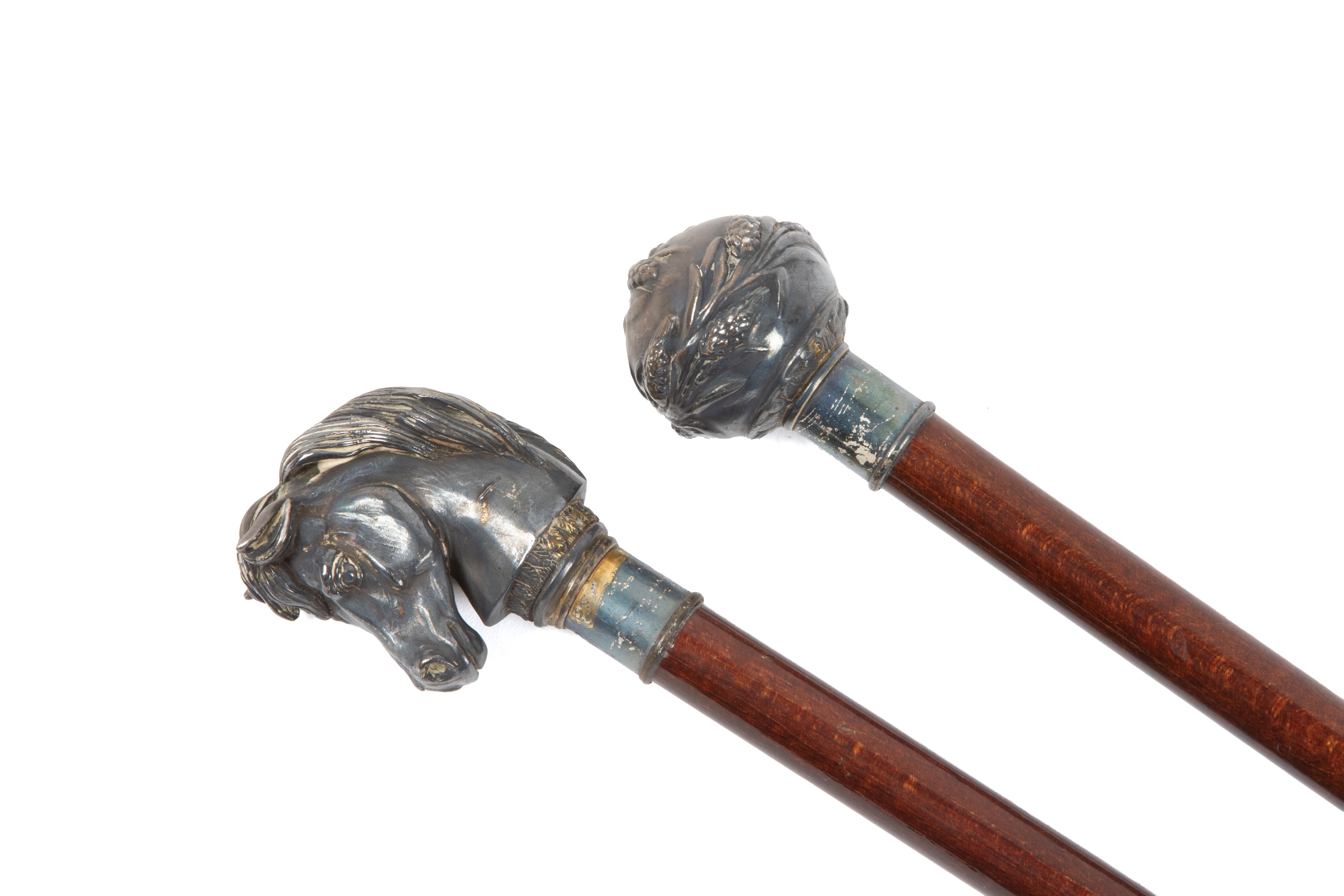 Due bastoni in mogano con impugnature a testa di cavallo e decorazioni floreali, XX secolo